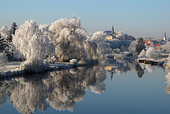 Winterliche Landschaft mit Stadt am See.